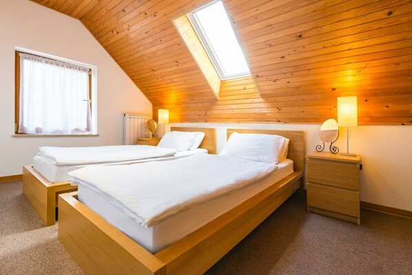 A bedroom with two beds, wooden ceiling, skylight, bedside lamps, and a window with curtains. - Lepa Soca House, Soca Valley (Bovec)