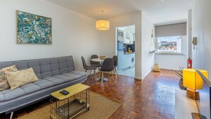 Un salon moderne avec un canapé gris, une petite table et une cuisine en arrière-plan.