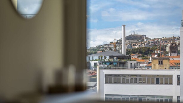 Une vue d’une ville avec ses bâtiments, une cheminée imposante et une colline en arrière-plan.