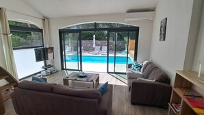 Un salon avec vue sur la piscine, un canapé, une table basse et un téléviseur.