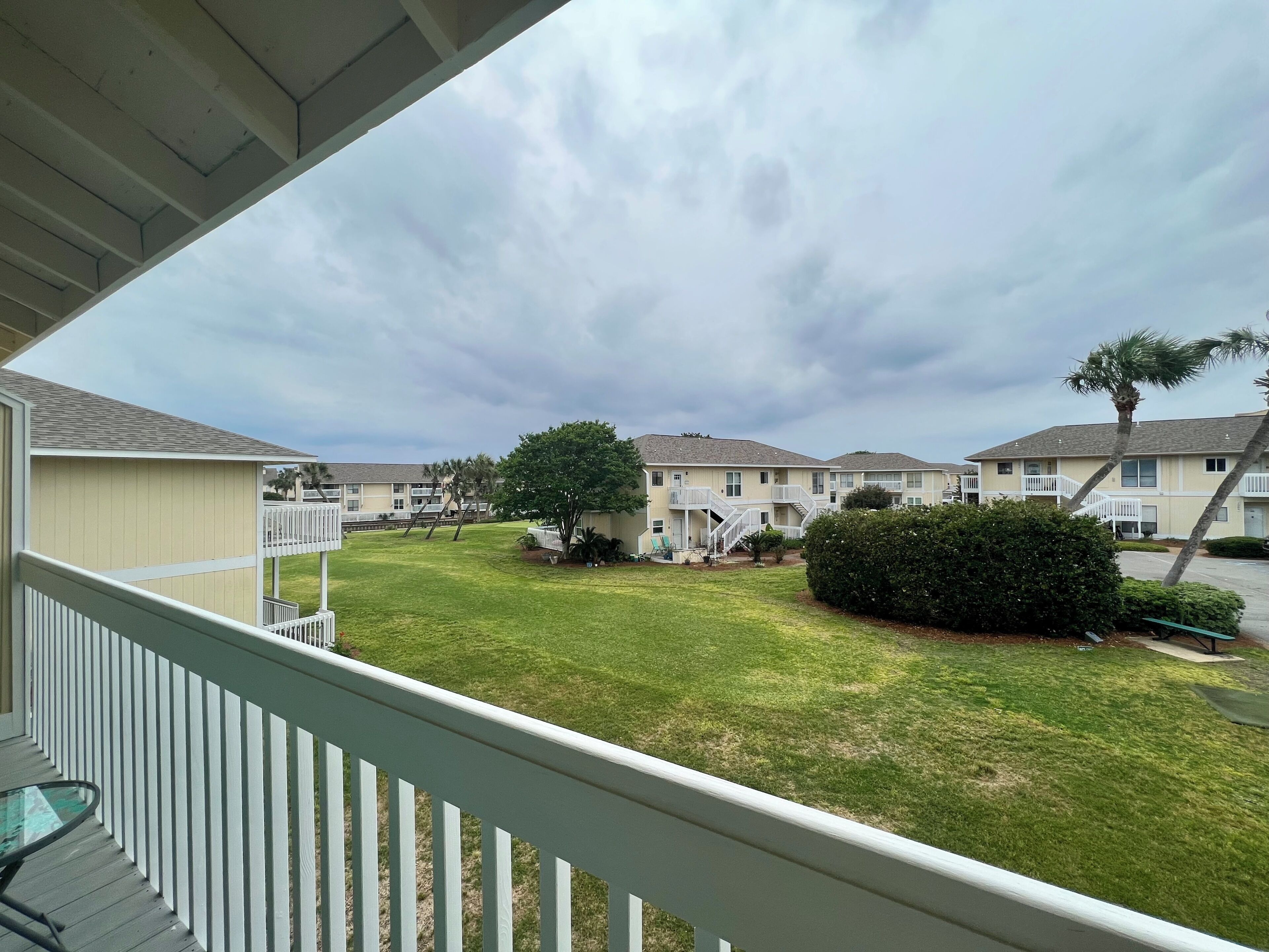 A residential area with multiple two-story houses, a grassy yard, and a white railing.