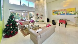 A spacious living room with a Christmas tree, a sofa, a coffee table, and a foosball table. - Aruba Villa Tropical (Noord)