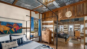 Une chambre à coucher rustique avec un lit, une commode et un tableau représentant des chevaux.