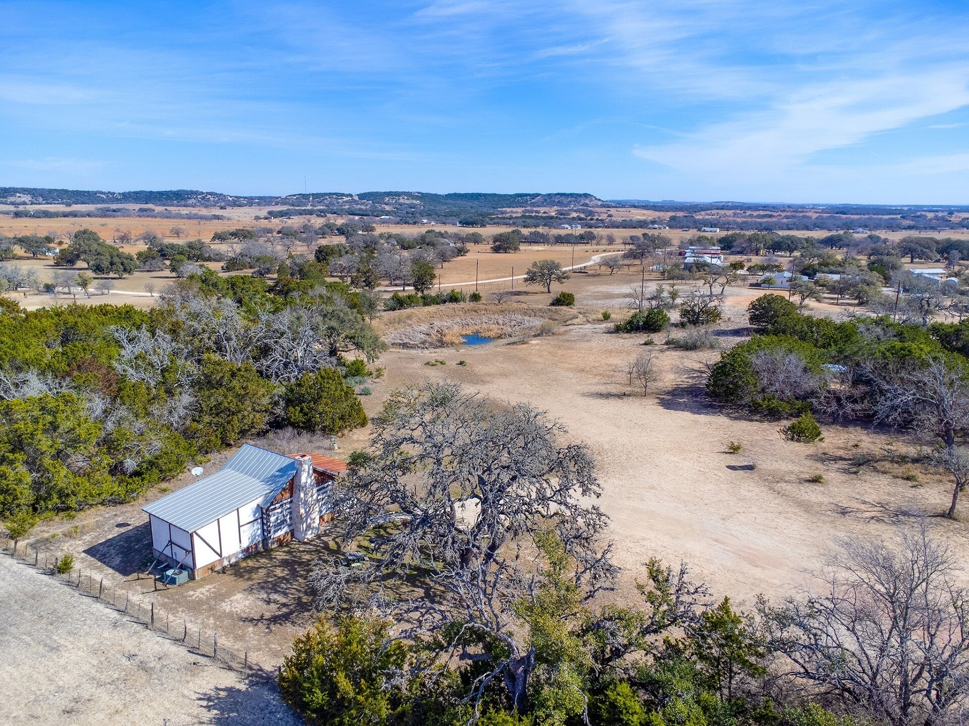 Un paisaje rural con un pequeño edificio rodeado de árboles y campos abiertos.