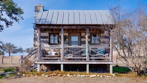 Une cabane rustique dotée d’une véranda, de murs en bois et d’un toit en métal.