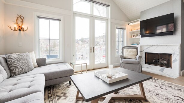 Una sala de estar moderna con un sofá gris, una mesa de centro y una chimenea.