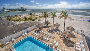 Ein Poolbereich mit Liegestühlen und Blick auf Strand und Meer.