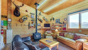 Interior acogedor de una cabaña con chimenea, sofás de cuero y diversas monturas de animales.