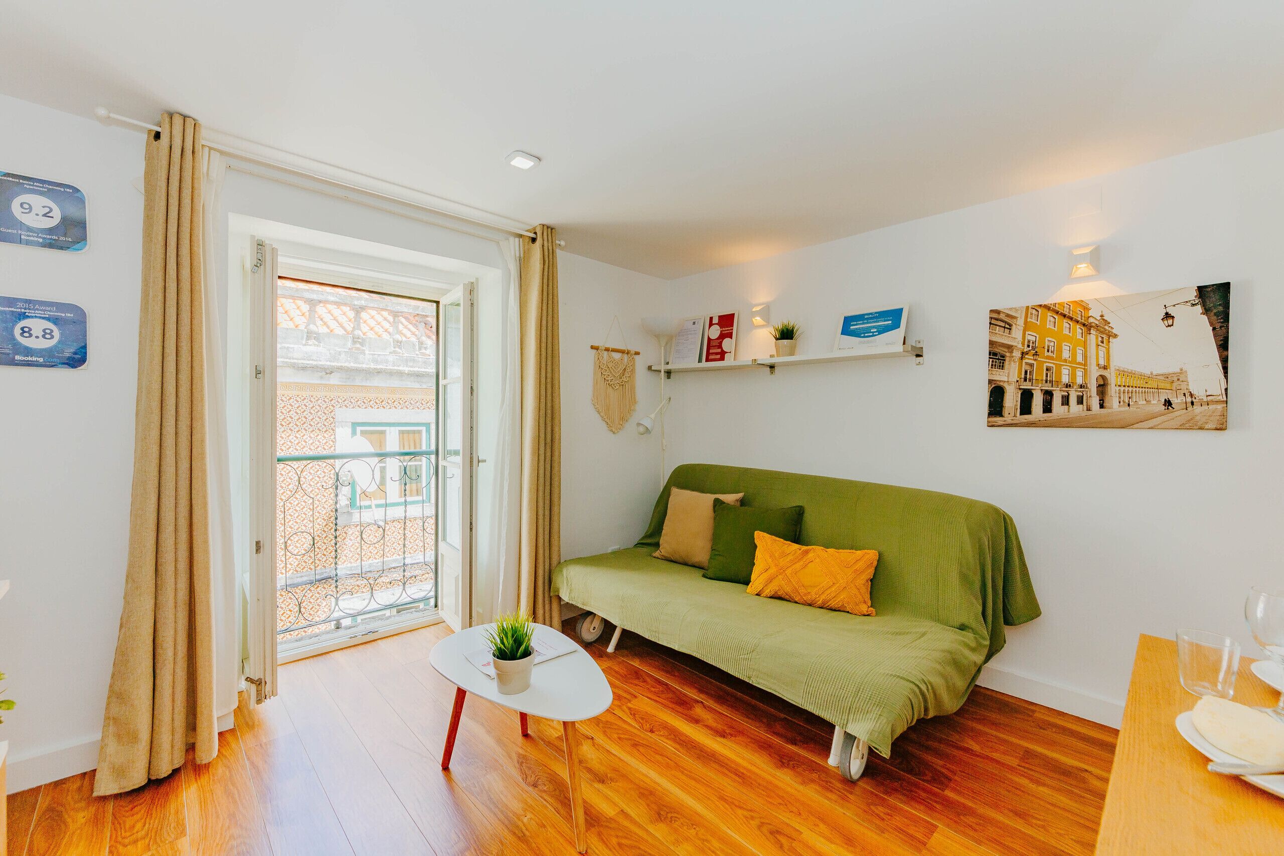En hyggelig stue med en grøn sofa, et lille hvidt bord med en plante, og en balkon med gelænder.