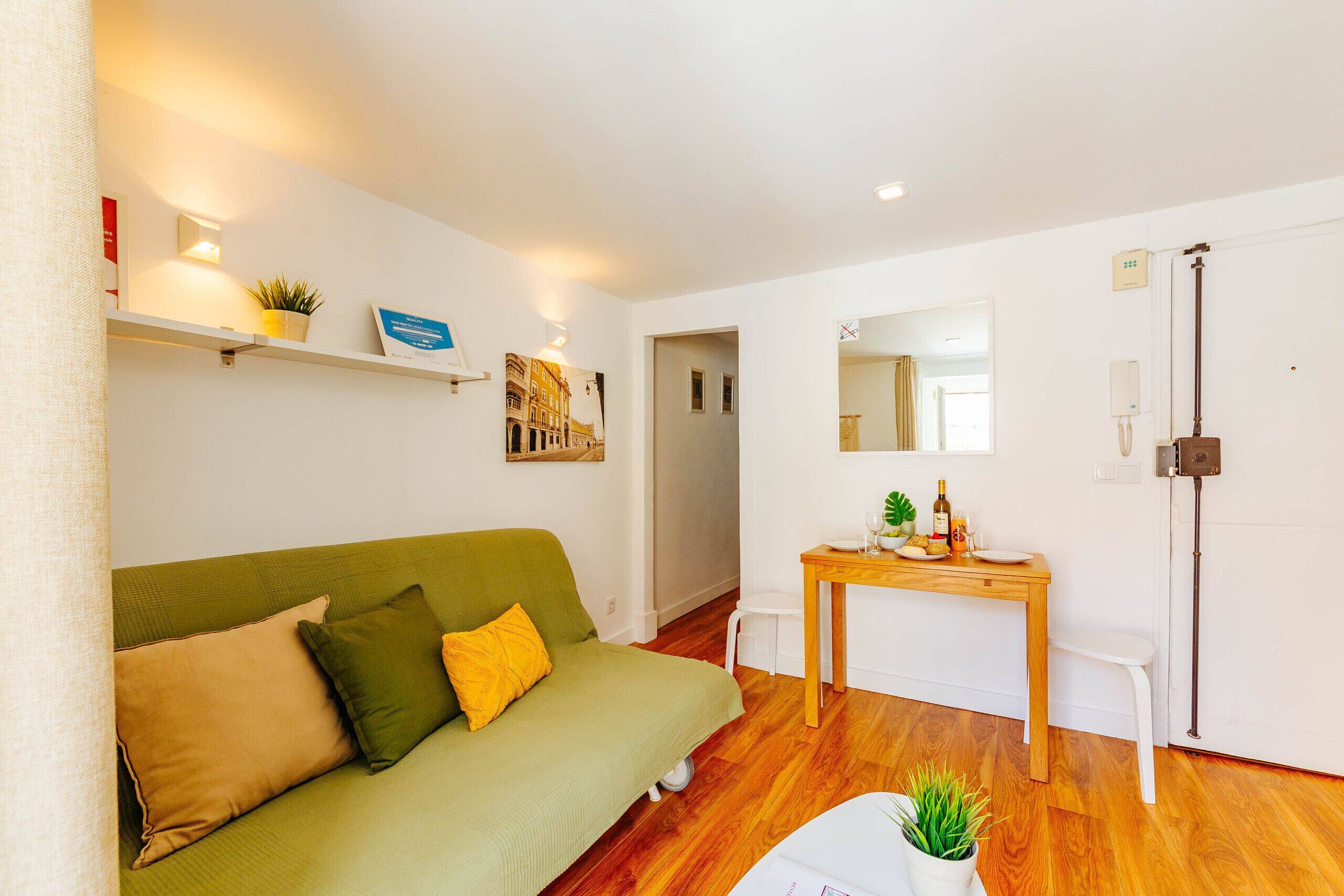 A room with a green sofa, a wooden table, and a white chair.