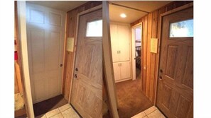 Enter a room with a door featuring a small window and a door handle, leading to a carpeted area and a closet with cabinets.