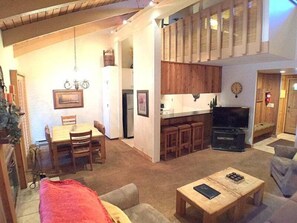 Cozy living space with a dining area, kitchen, and seating area, featuring a wooden table, sofa, and coffee table.