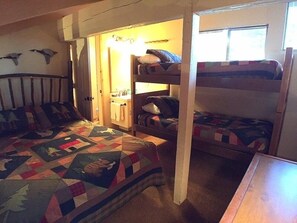 Cozy bedroom with bunk beds, featuring a lower bed with a wooden headboard and a quilted bedspread.