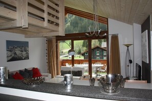 Eine moderne Küche mit großem Fenster, Holzbalkendecke und Blick auf ein Haus.