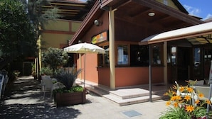 A building with a covered entrance, outdoor seating, and potted plants. - Albergo Hotel Primavera (Senigallia)