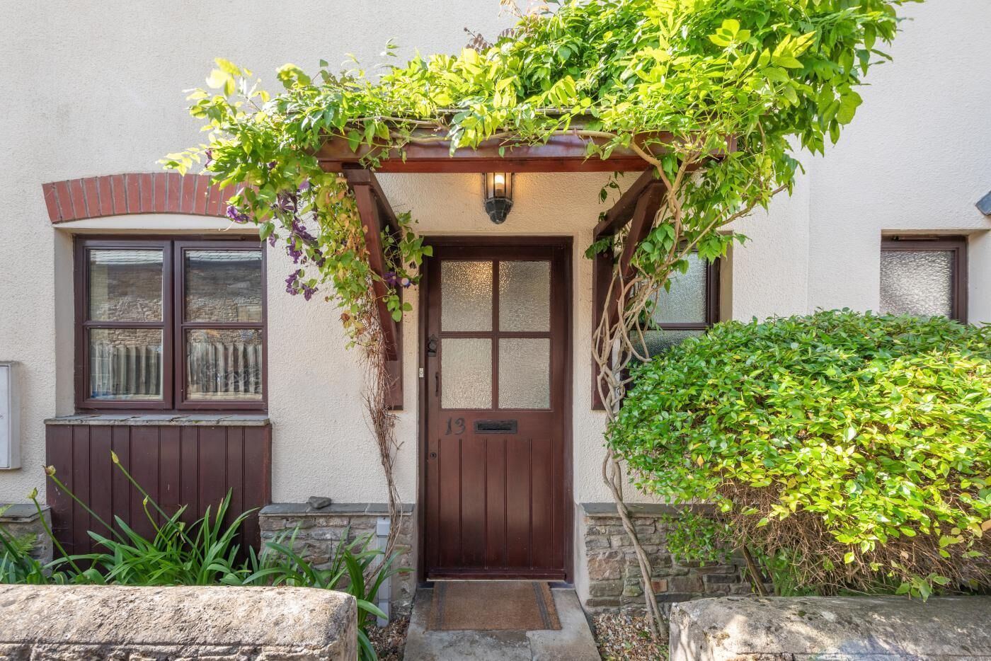 A house with a brown door, a small porch with a wooden railing, and a brick archway above the door.