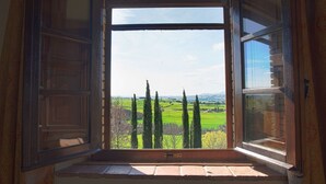 A room with a large window, a wooden bench, and a view of a green landscape with trees. - Typical Stone House looking Banfi Wineries (Cinigiano)