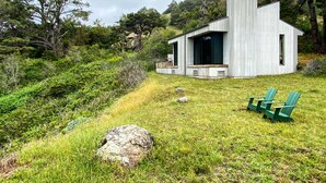A modern house with a large chimney, surrounded by lush greenery and a grassy lawn.