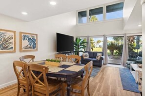 A spacious living area with a dining table, chairs, a flat-screen TV, and a sofa. - Unit 17, Spacious 2 bedroom Beach Condo with Loft (Panama City Beach)