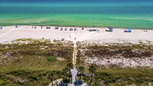 A beach with a clear view of the ocean, a sandy path leading to the water, and several beach umbrellas and chairs. - Unit 17, Spacious 2 bedroom Beach Condo with Loft (Panama City Beach)