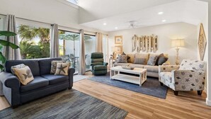 A spacious living room with a dark sofa, a patterned armchair, and a coffee table. - Unit 17, Spacious 2 bedroom Beach Condo with Loft (Panama City Beach)