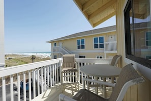 Enjoy the ocean view from this balcony with a round table and two chairs.