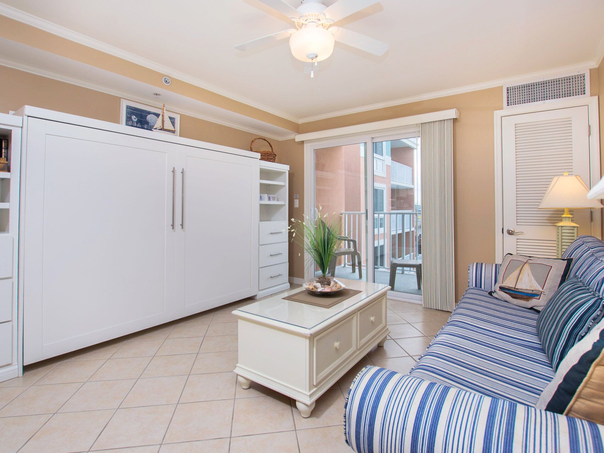 Een woonkamer met een bank, een salontafel, een kast en uitzicht op een balkon.