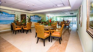 A spacious dining area with wicker furniture and a mural of a beach scene. - Modern efficiency unit located on 42nd street, close to beach and convention center! (Ocean City)