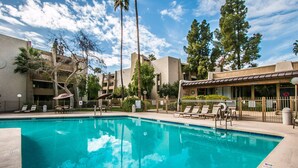 A swimming pool with lounge chairs and umbrellas, surrounded by buildings and trees. - Beautiful Southwest Style Old Town Scottsdale, Ground Level Condo (Scottsdale)