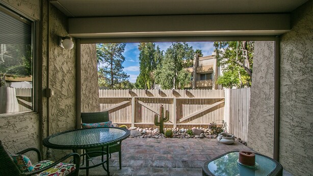 An outdoor patio with a glass table, wicker chairs, and a cactus in the background. - Beautiful Southwest Style Old Town Scottsdale, Ground Level Condo (Scottsdale)