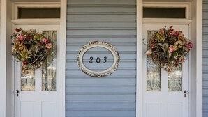 A house number 203 on a blue door with two decorative wreaths on either side.