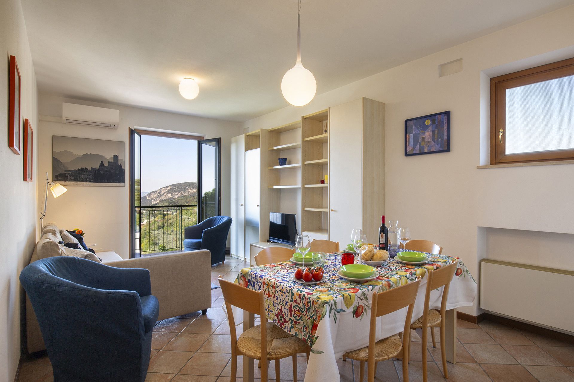 A dining area with a table set for four, chairs, a television, and a view of the outdoors.