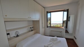 Een hotelkamer met een bed, nachtkastje, lamp, raam met uitzicht en een inbouwkast.
