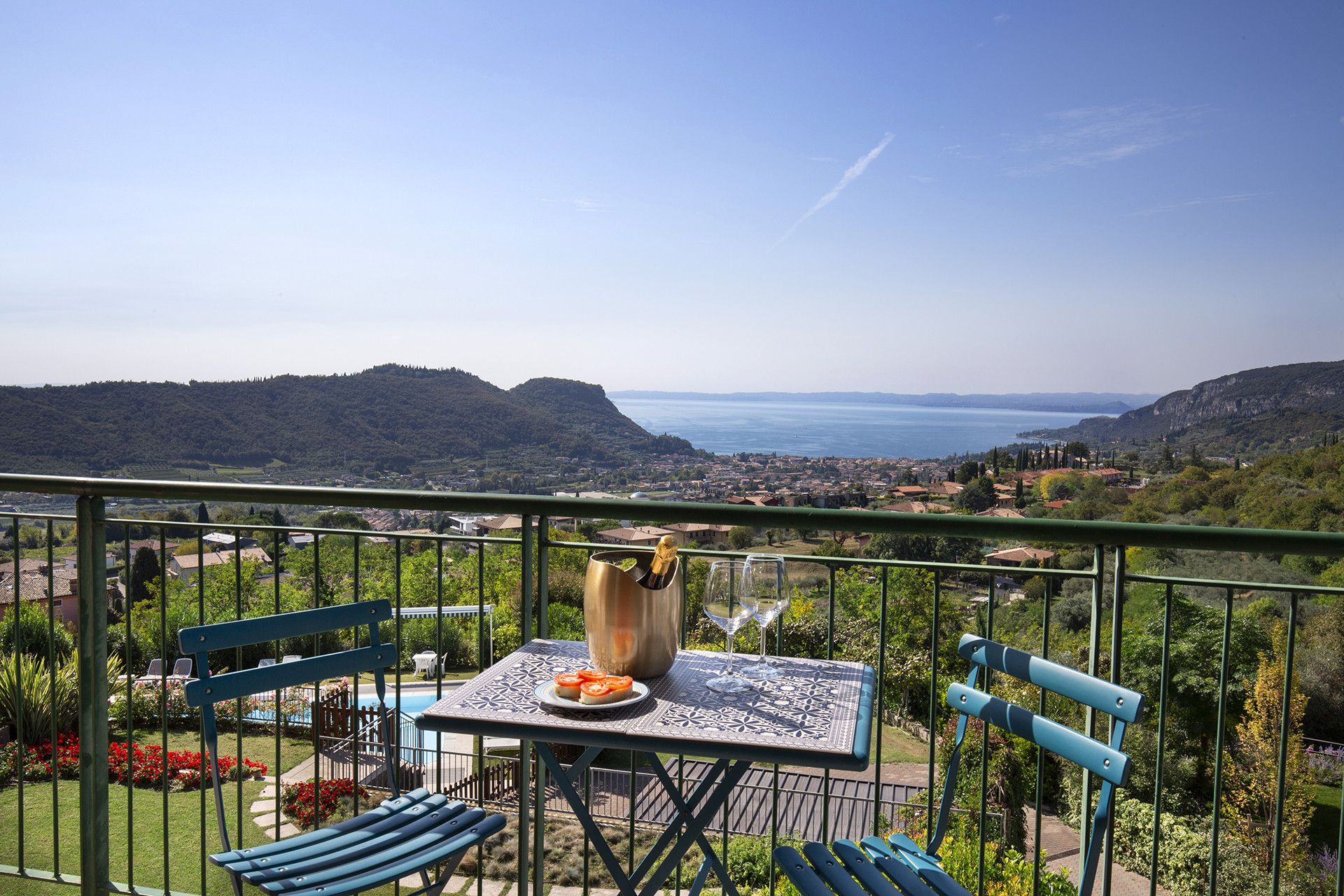 Un balcon avec une table, des chaises et une vue sur un lac et des montagnes.