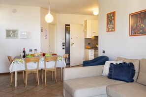 A dining area with a table set for four, a sofa, and a kitchen in the background.