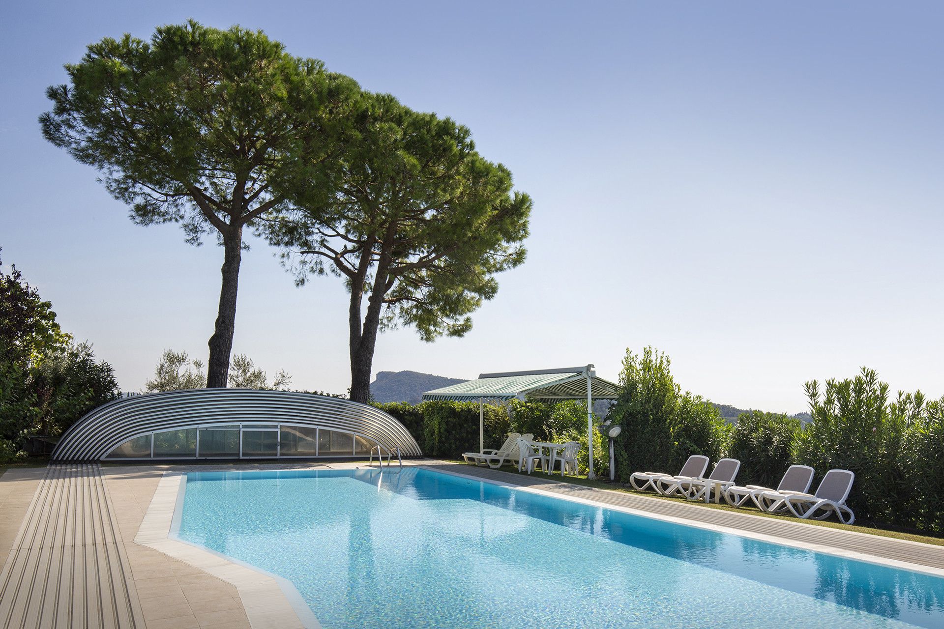 Una piscina con sillas de descanso y una estructura de vidrio.