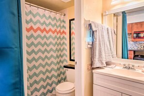Un bagno con un water bianco, un lavandino con uno specchio e una tenda della doccia a motivi a zig zag.