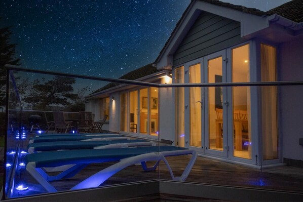 A modern house with a swimming pool, large glass doors, and a starry night sky. - 3 Bed in Croyde (oc-reeds) (Croyde)