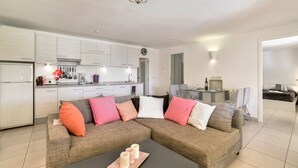 Ein modernes Wohnzimmer mit einer Eckcouch, einem Couchtisch und einer Küche im Hintergrund.