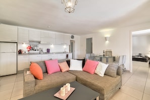 Ein modernes Wohnzimmer mit einer Eckcouch, einem Couchtisch und einer Küche im Hintergrund.