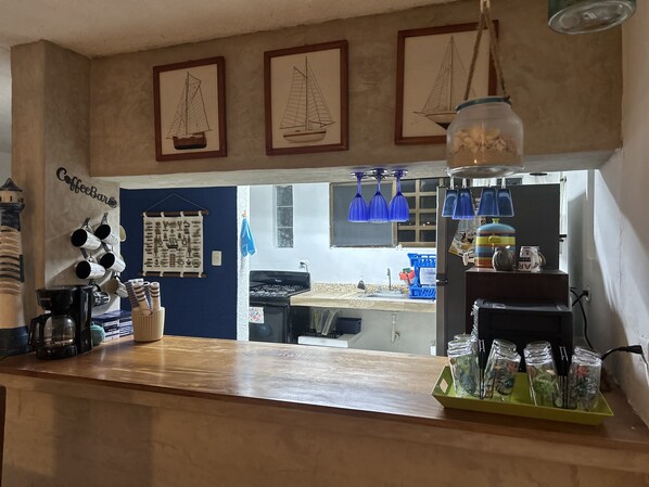 A kitchen counter with a coffee machine, mugs, and a coffee bar sign.
