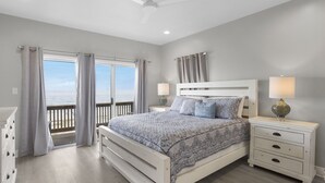 A bedroom with a bed, nightstands, and a view of the ocean. - Reserve now. Beautiful pool and ocean. Easy social distancing. Huge pool deck. <br> (Fort Morgan)