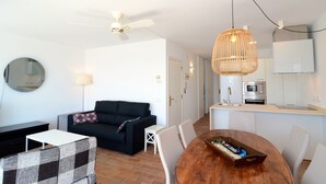 A modern living room with a black sofa, a round coffee table, and a dining area with a wooden table and chairs. - ESCORPORA (Estartit)