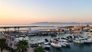 A marina with boats docked, a bridge in the background, and a calm sea. - ESCORPORA (Estartit)