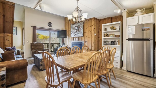 Une cuisine spacieuse avec une table à manger en bois, des chaises, un four encastré et une grande fenêtre donnant sur l’extérieur.