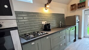 A kitchen with a built-in stove, a coffee maker, and a refrigerator. - A 1 bedroom cottage that sleeps up to 4 with heated covered pool (Henansal)