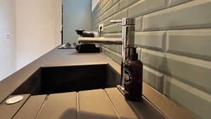 A modern kitchen with a built-in sink, a bottle of beer, and a window above the sink. - A 1 bedroom cottage that sleeps up to 4 with heated covered pool (Henansal)