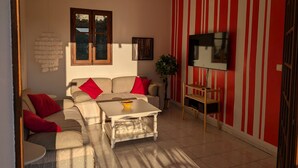 A living room with a sofa, a coffee table, a TV, and a red-striped wall.