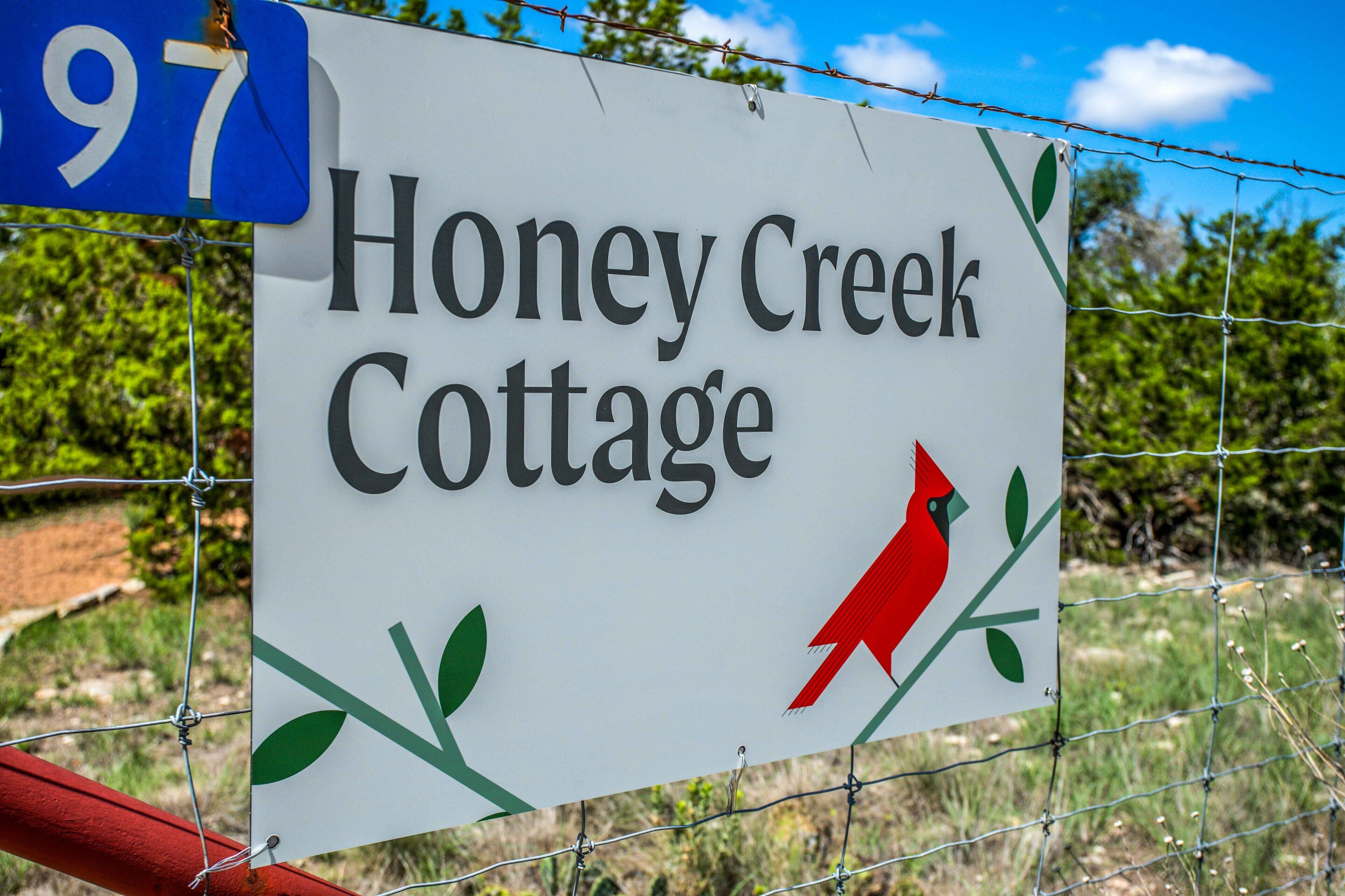 Señal para Honey Creek Cottage, con diseño de aves cárdinal y follaje.