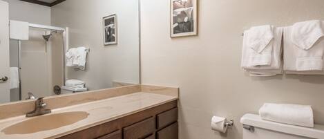 A bathroom with a sink, mirror, toilet, and towel rack.